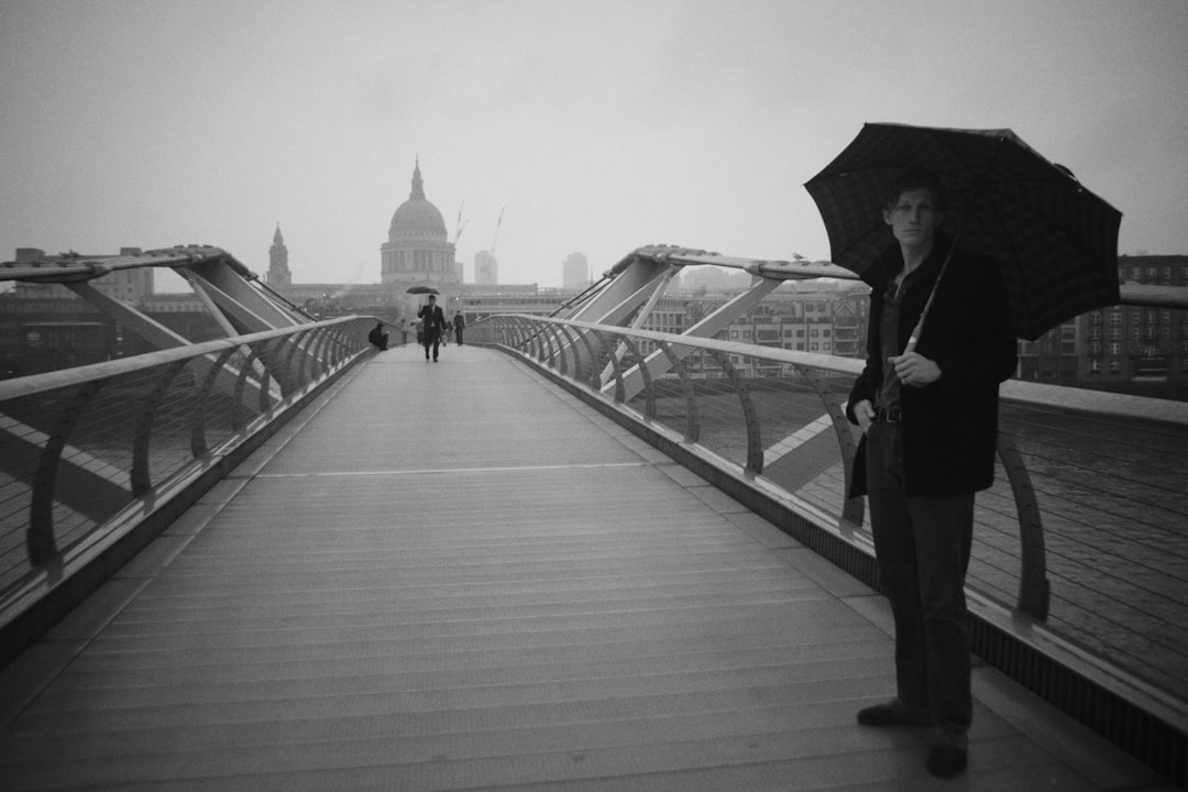 Walking across Millennium Bridge, London on a rainy day. November 2023.